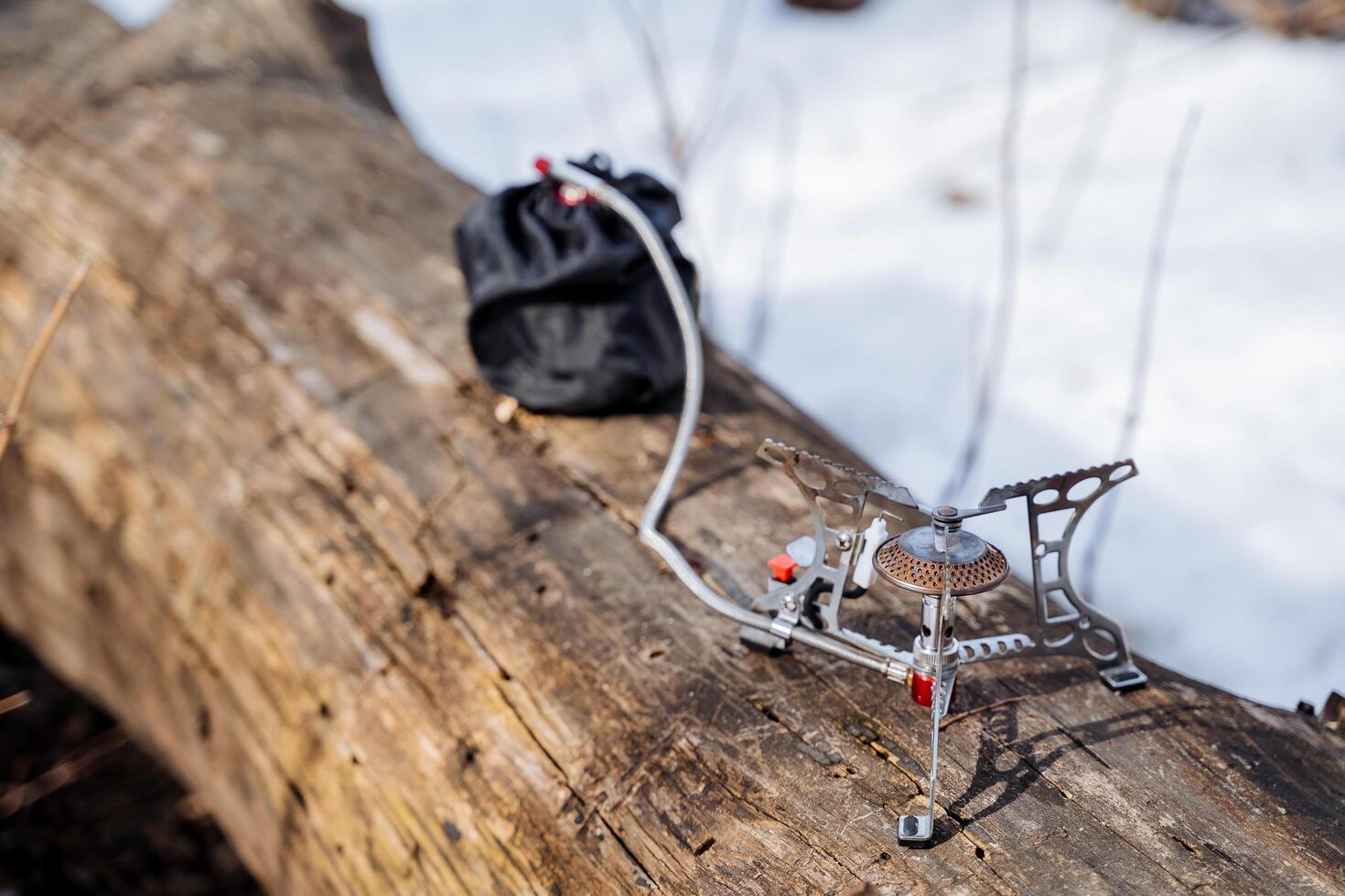 Tourist burner stands on a log, cooking on a hike, camper's equipment, gas in a bag, light gas burner photo