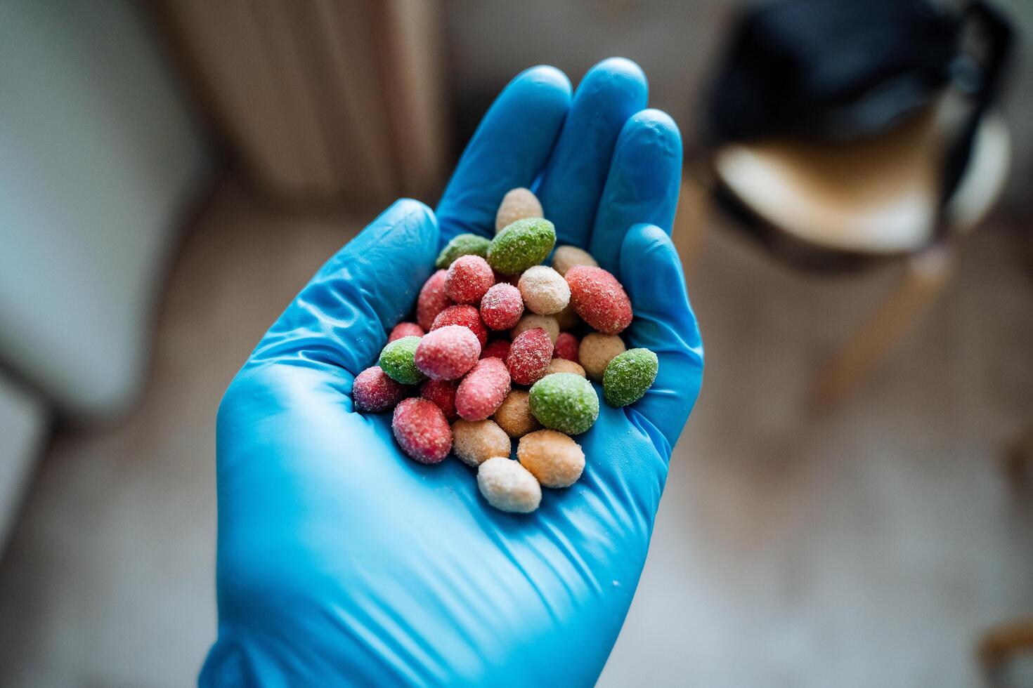 A handful of peanuts colored hand in a glove. Salted nuts are bright in color. The dragee is poured into the hand. Chemical product in a protective glove. photo