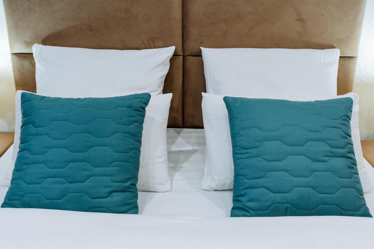 el cabeza de el cama, un conjunto de almohadas en el dormitorio, azul almohadas, blanco cama lino, fundas de almohada de diferente colores, un hotel habitación, noche Encendiendo en el habitación. foto
