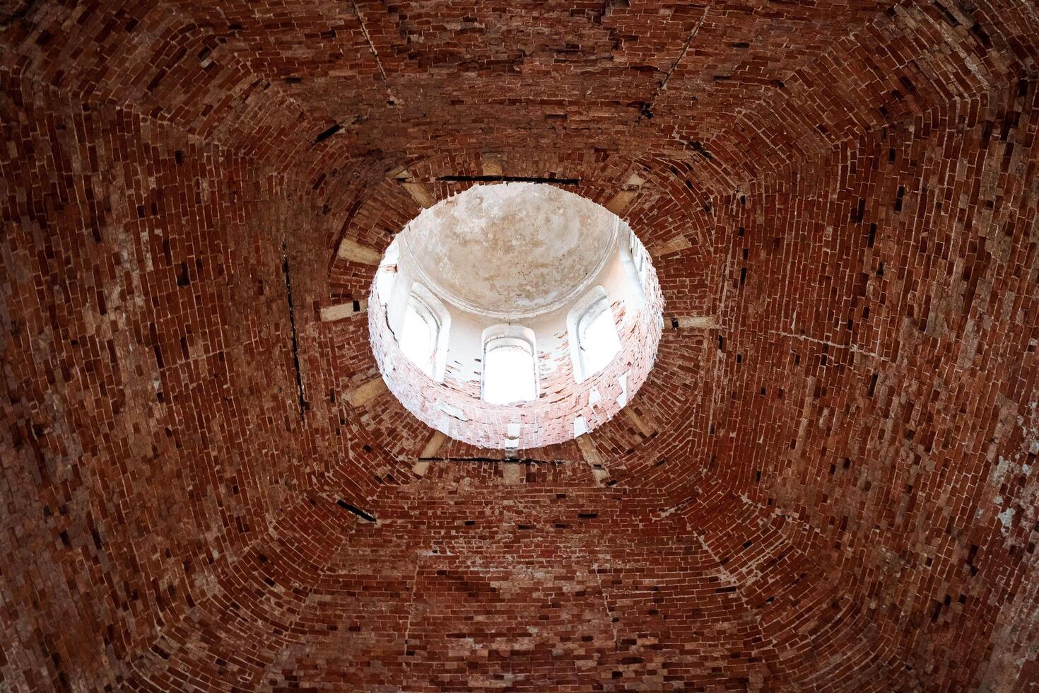 A round hole in the ceiling of an old building, a brick vault of an ancient temple, a church inside, red brick masonry. photo