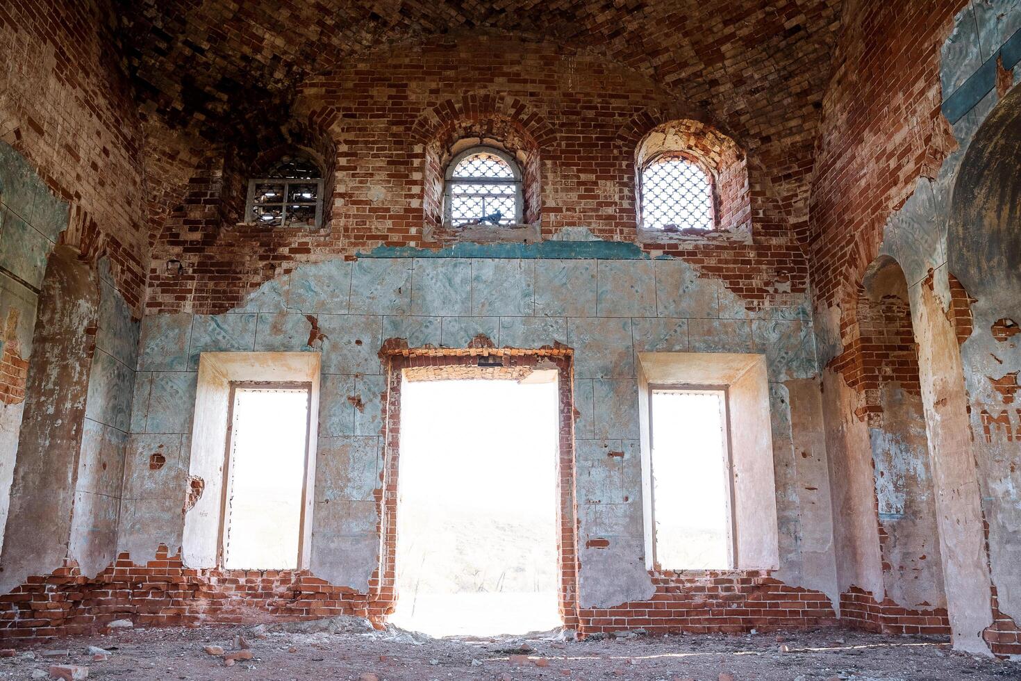 The old temple is viewed from the inside, the abandoned church, the broken windows, the bright sunlight falls into the windows, the ancient walls of the building, the red brick, photo