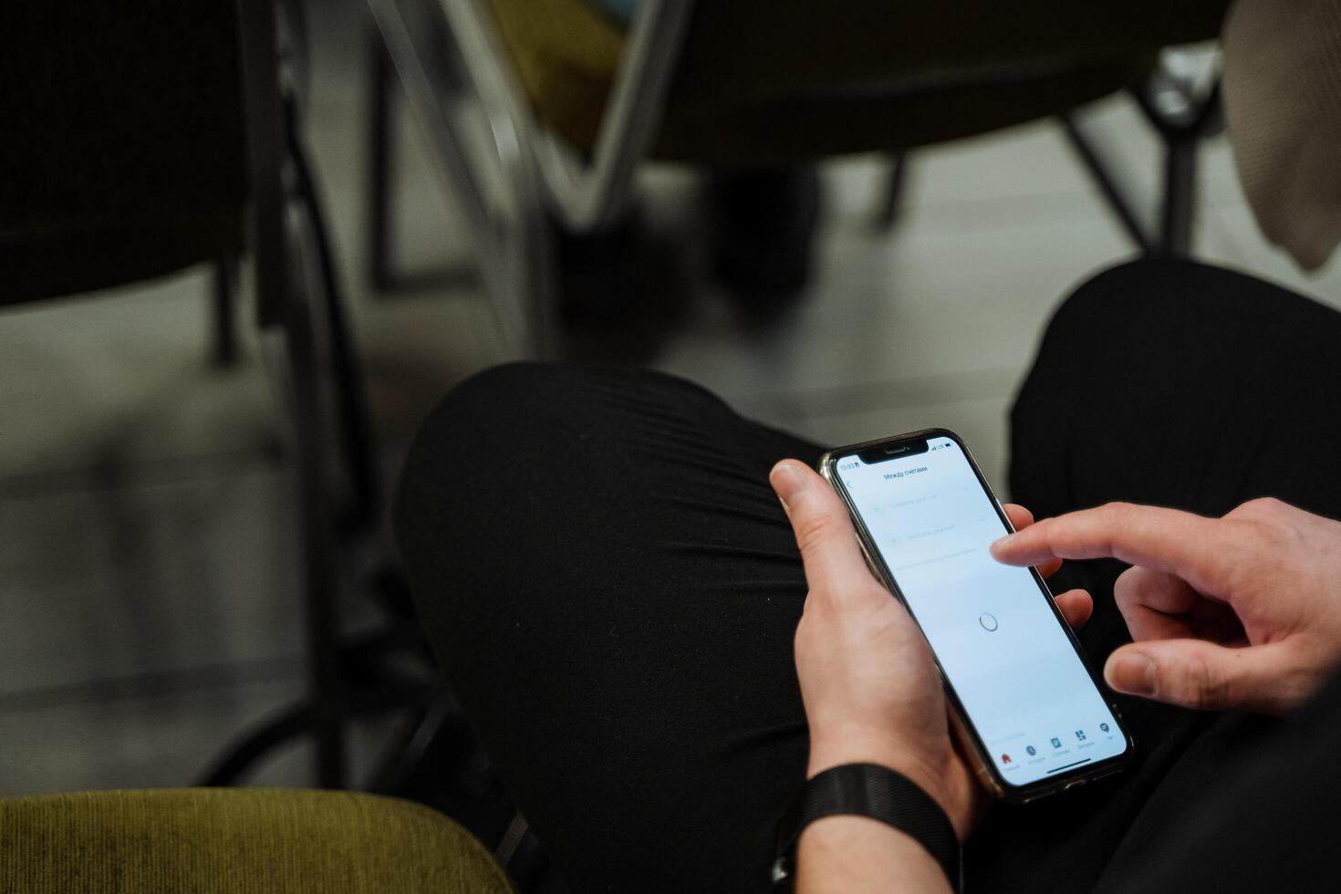 Poke your finger at the phone screen. The guy types text on his smartphone. The cell phone screen is included. Hands hold the gadget. White color of the instrument panel. photo