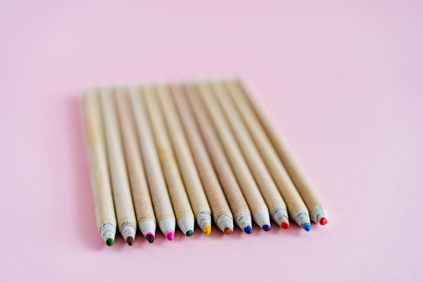 On the pink table are bright colored pencils. A set of pencils for drawing. To develop creative skills in children. Pencils made of natural wood photo