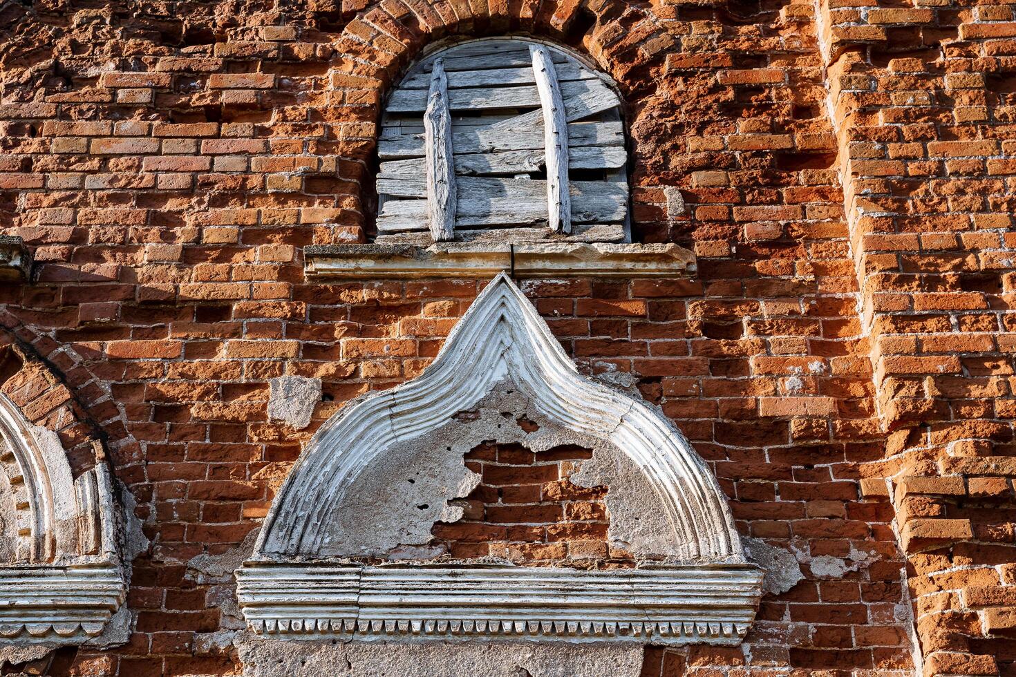 Stucco on the facade of the old building, the ancient structure of the house view from the street, a beautiful pattern on the wall of the historic house, a fragment of plaster red brick. photo