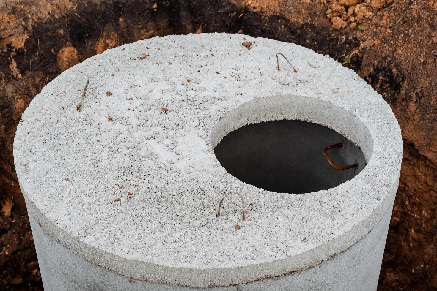 Concrete well sewerage, round-shaped lid made of cement, septic tank for dirty water, installation of concrete rings, photo