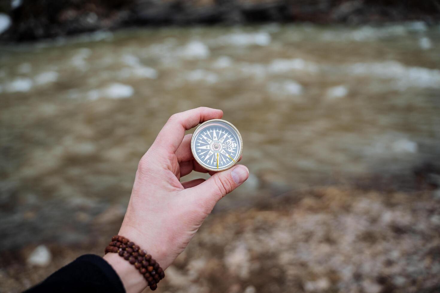 Orienteering in an open area with a compass, the hand holds the compass arrow points north. Survival in the woods, bushcraft. photo