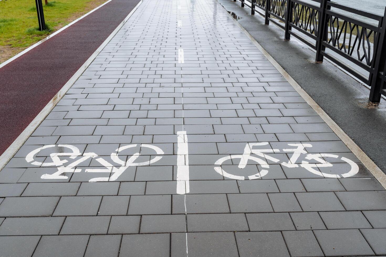 Bicycle path, drawing of a bicycle on the sidewalk, marking of the movement of cyclists on the asphalt in the city park, road sign bicycle photo