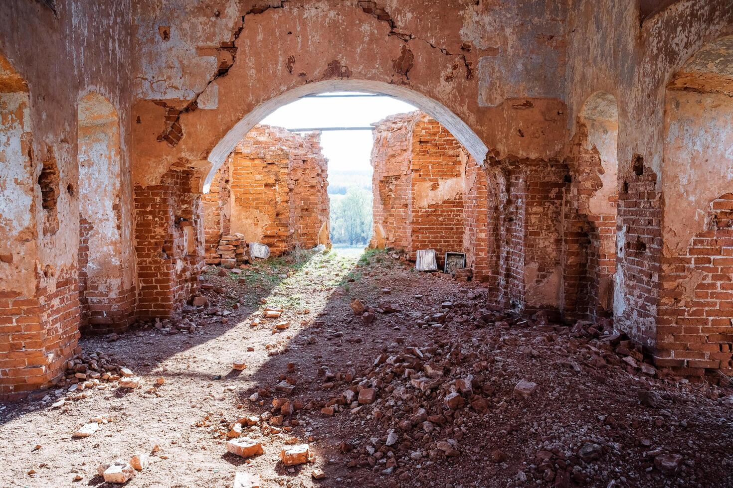 The interior of the old ruined Orthodox church, the sun shines through the destroyed window in the wall, the ancient walls are red brick, the destruction of the historical monument. photo