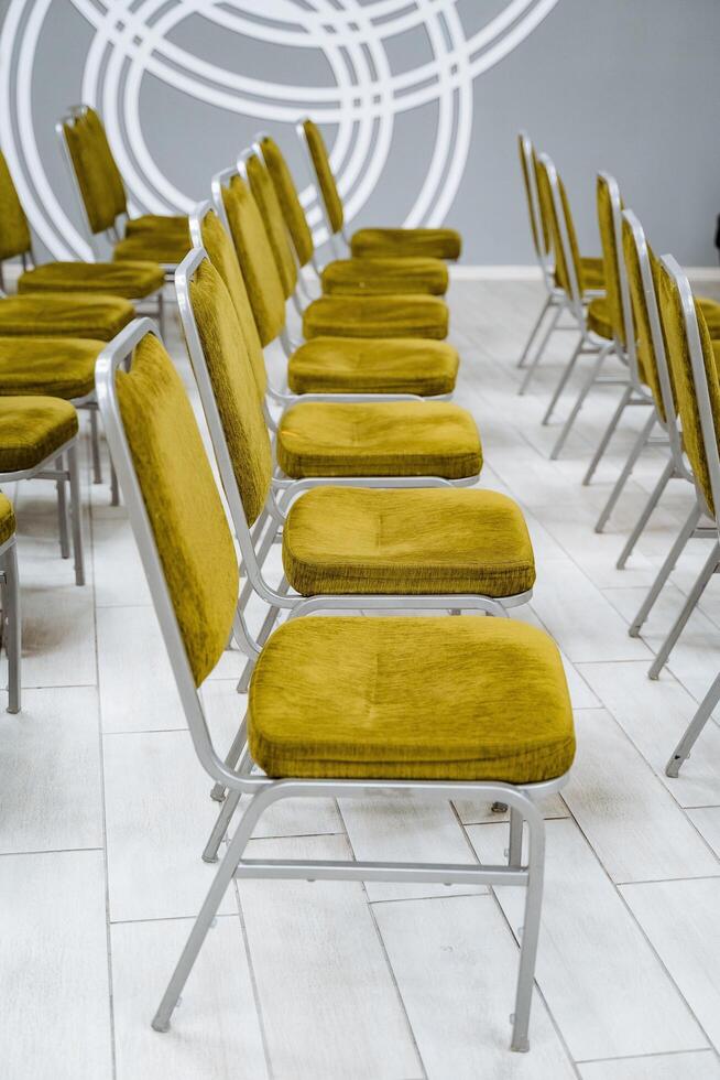 Green chairs stand in rows. Smooth structure, hall for events, classroom, auditorium. photo