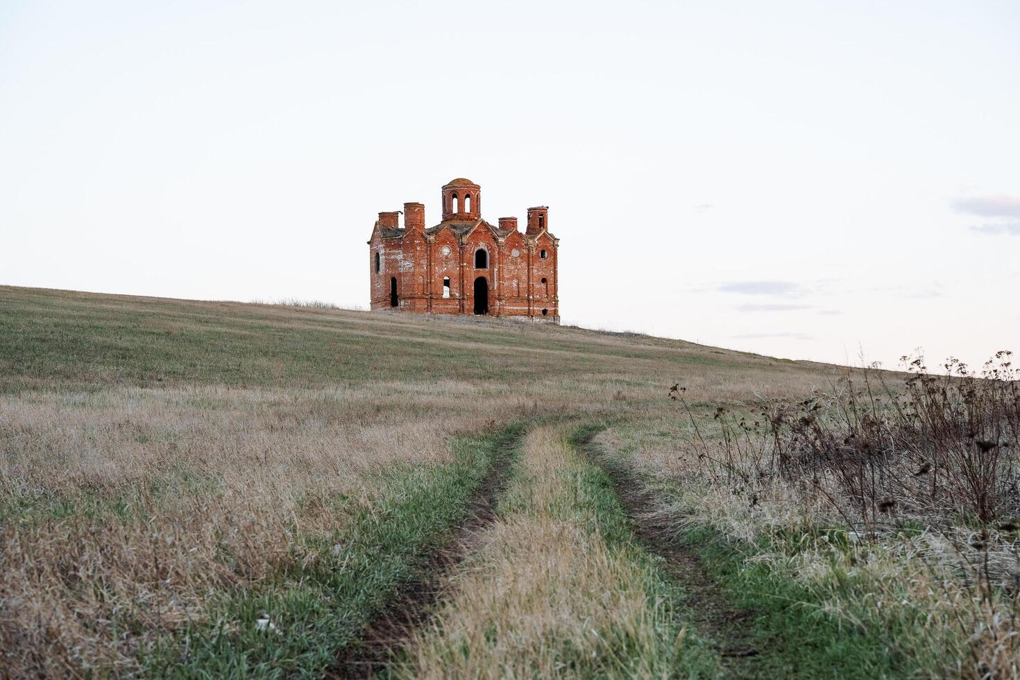 The old church stands in an open field, a ruined ancient temple, the ruins of an Orthodox church, a place for worship, a Christian shrine, a road up photo