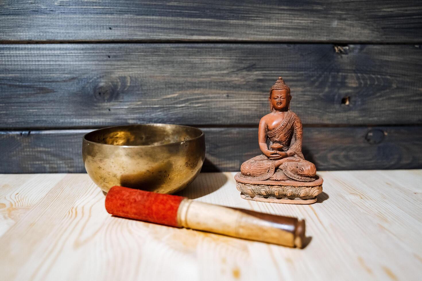 A Tibetan singing bowl and statue of Buddha on the floor. Meditation at home. A subject for meditation and healing sounds. Zen practice.Calm and tranquillity photo