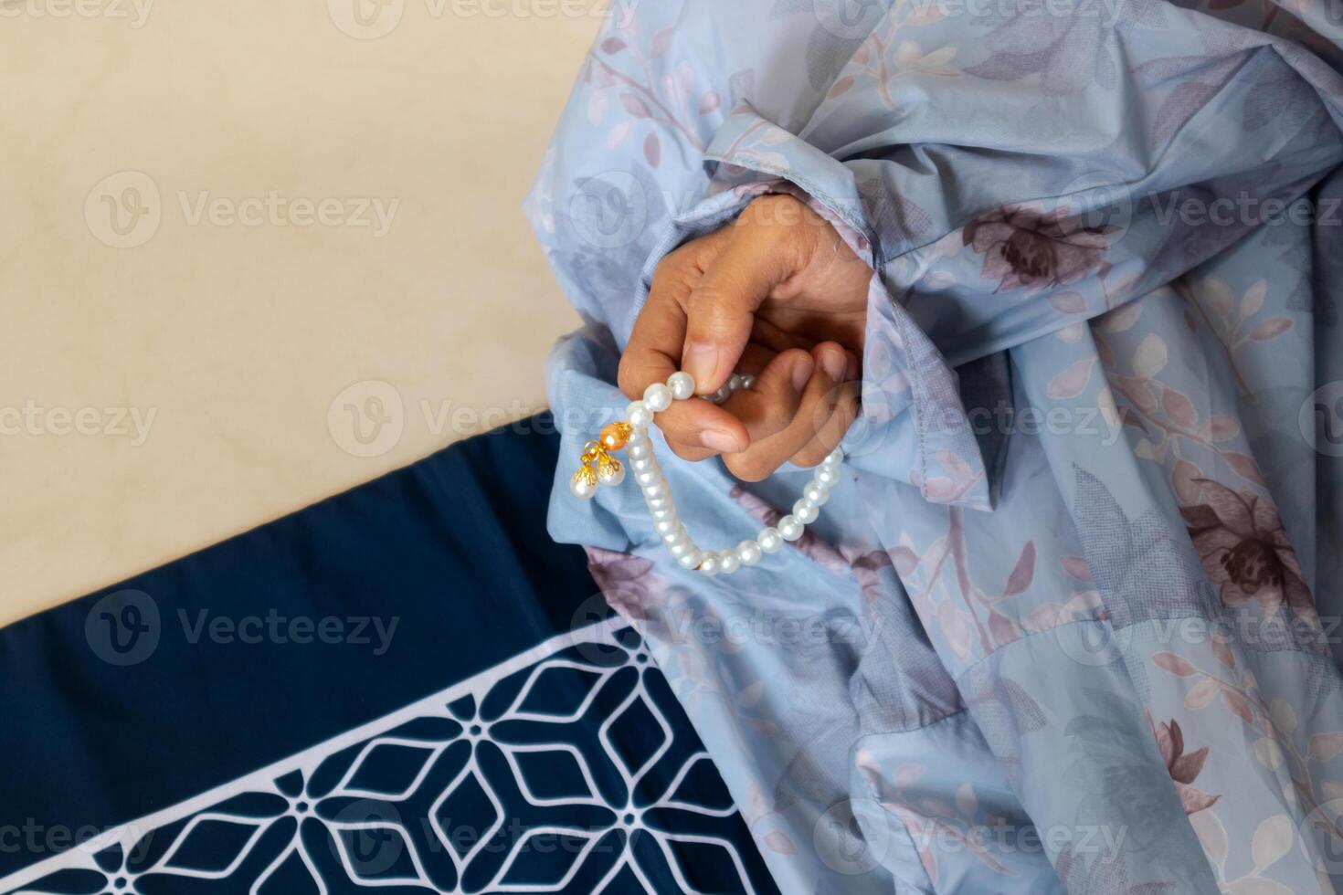 A Muslim woman wearing a moslem clothes with hijab called mukena and holding prayer beads for praying or dhikr photo