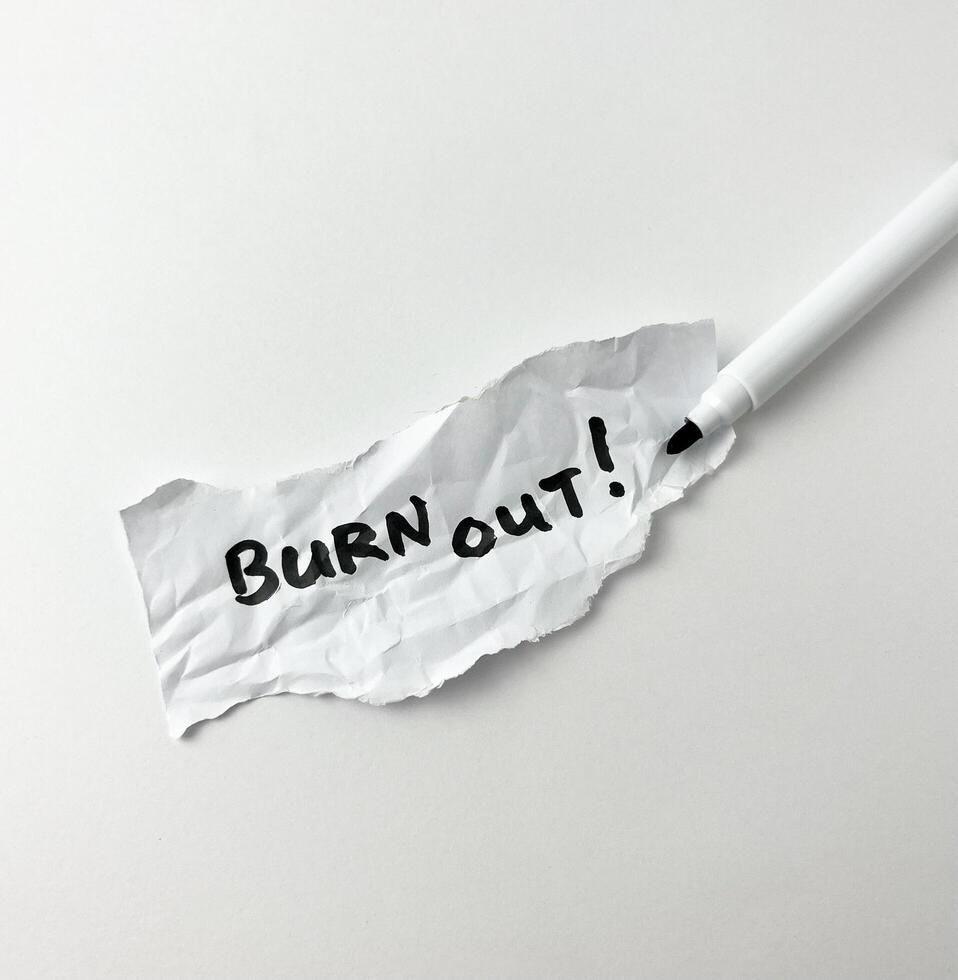 Burn out stressed out saying from tiredness of working handwriting with black marker isolated on crumpled ripped off paper on white background. photo