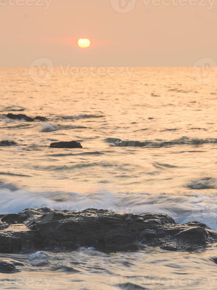 Sea sunrise with rock on beach photo