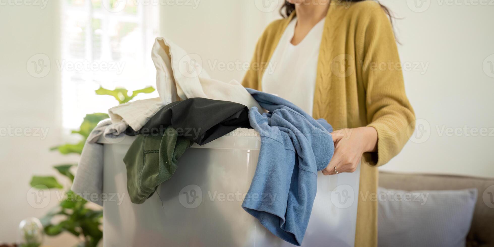 Donation, asian young woman sitting pack object at home, putting on stuff into donate box with second hand clothes, charity helping and needy people. Reuse recycle photo