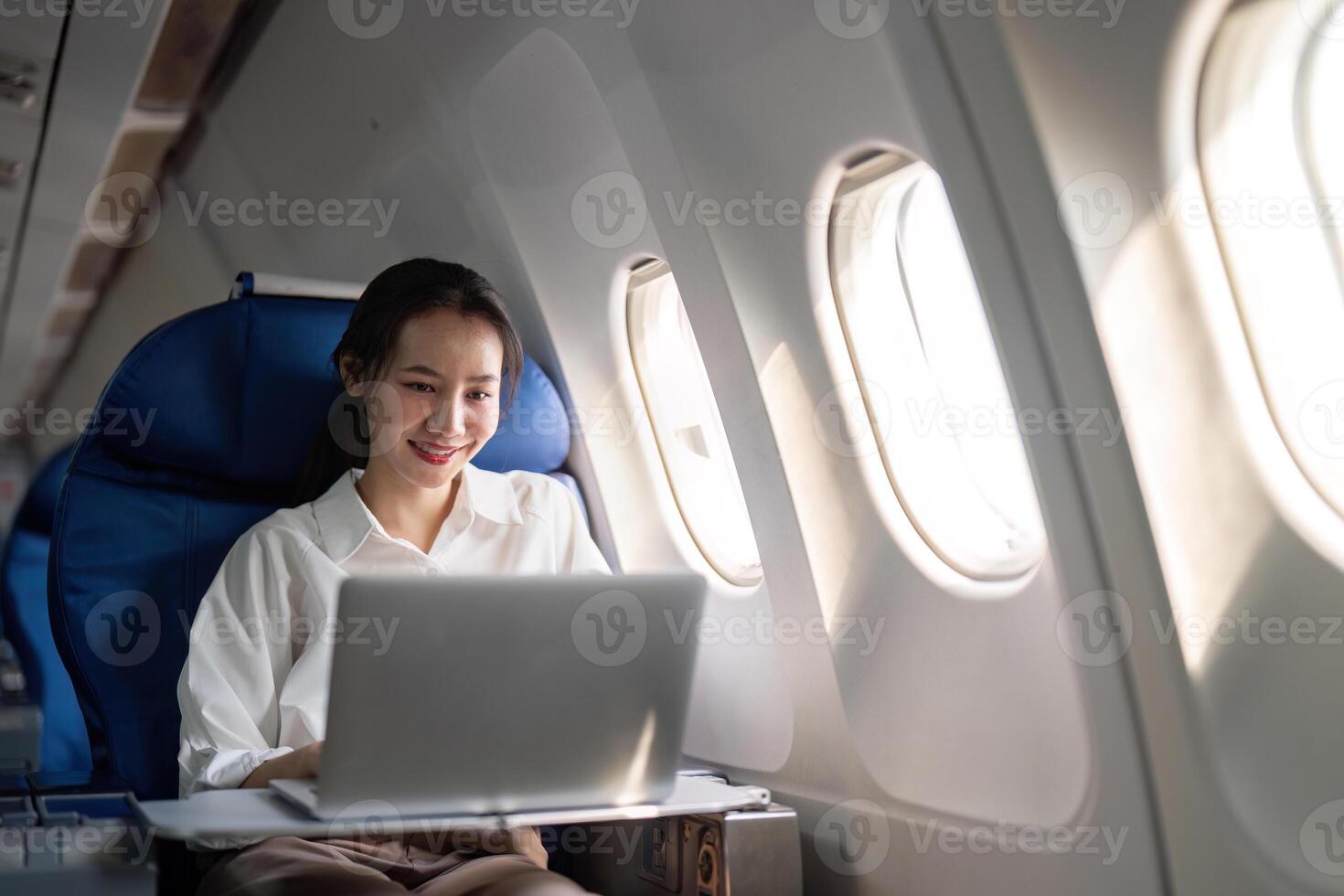 Successful young asian business woman sits in airplane cabin plane and working from anywhere. Flying at first class photo