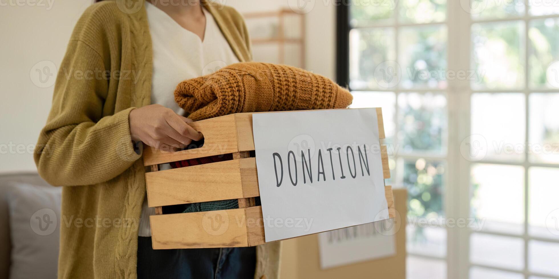 Donation, asian young woman sitting pack object at home, putting on stuff into donate box with second hand clothes, charity helping and needy people. Reuse recycle photo