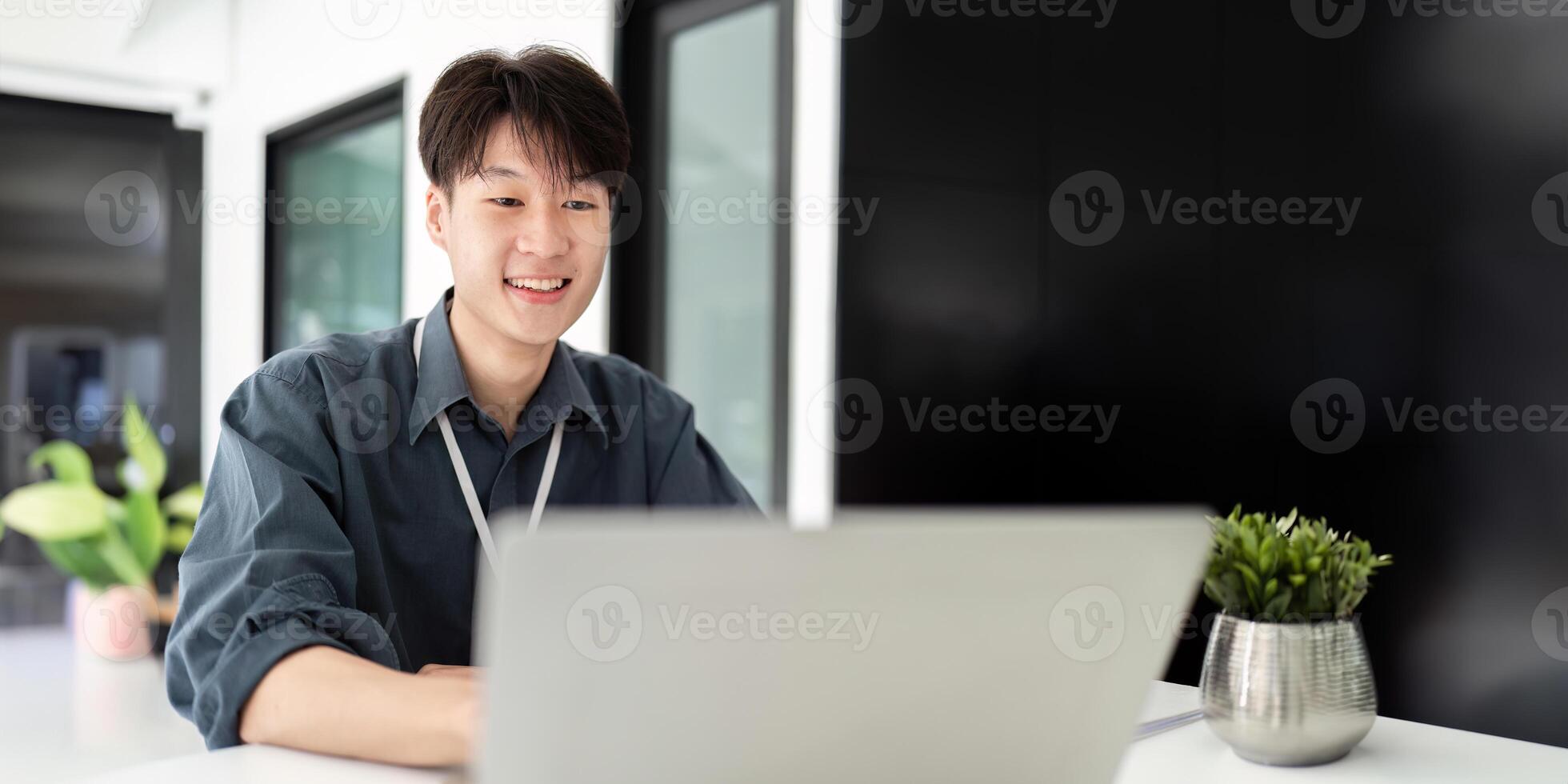 Businessman using laptop computer in office, Happy young asian businessman in modern office looking on laptop photo