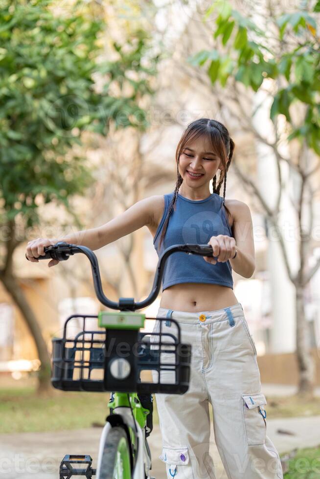 Happy young asian woman in casual clothes enjoy riding bicycle at the park for recreation photo