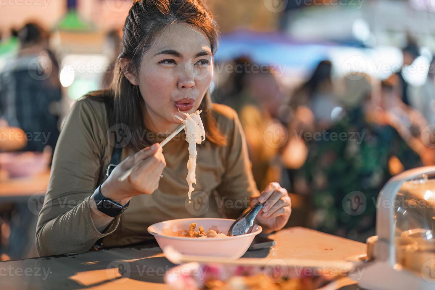 Traveler Asian woman enjoy eating noodle at night market. traditional Chiang Mai Thailand street food. photo