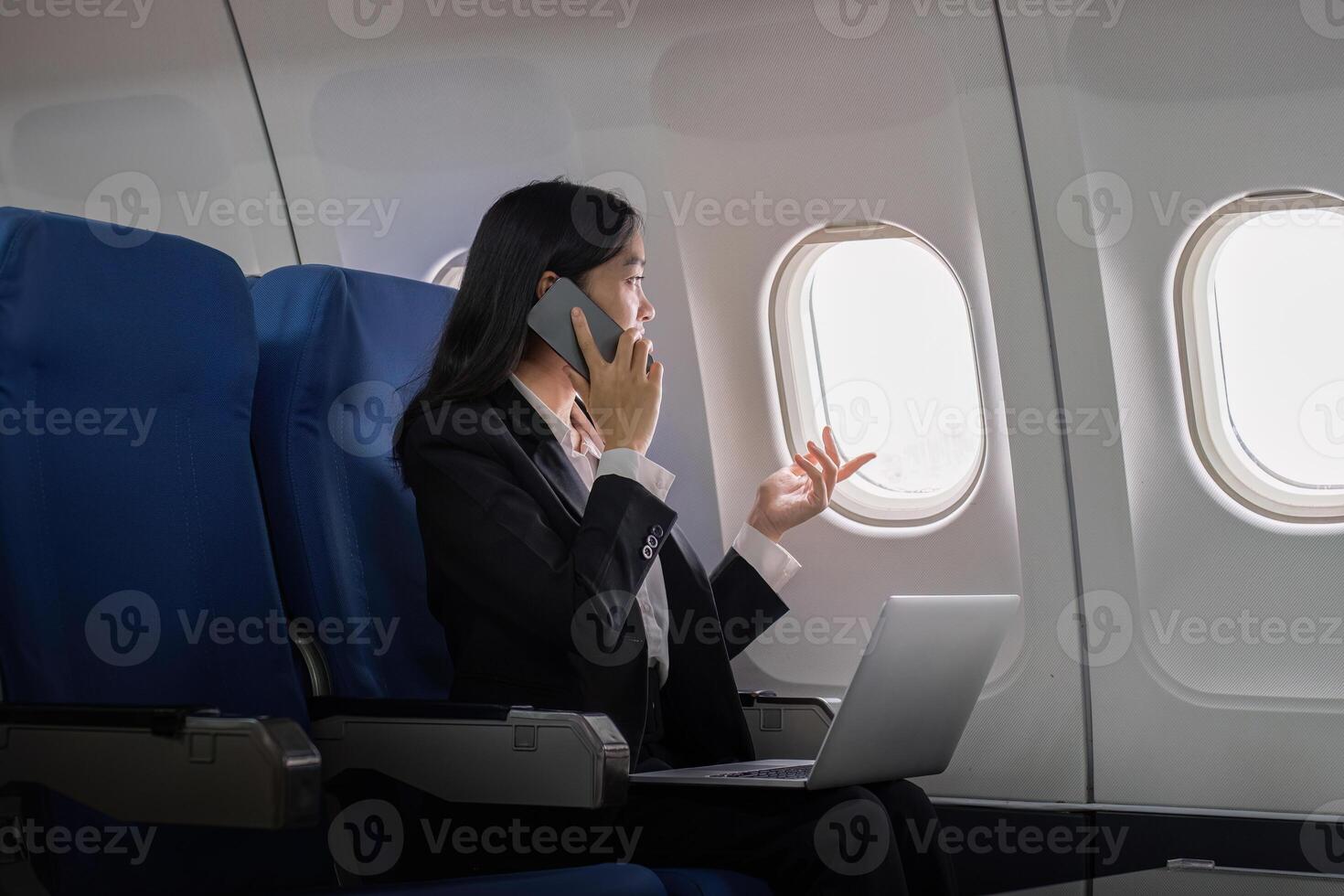Successful young asian business woman sits in airplane cabin plane and working from anywhere. Flying at first class photo