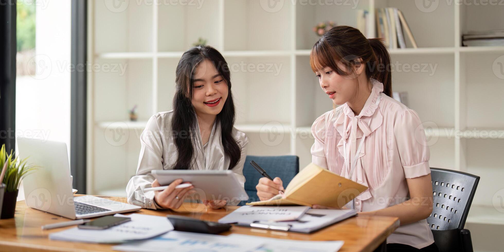Two Asian businesswoman working with laptop computer and discussing documents and idea at meeting. Teamwork process photo