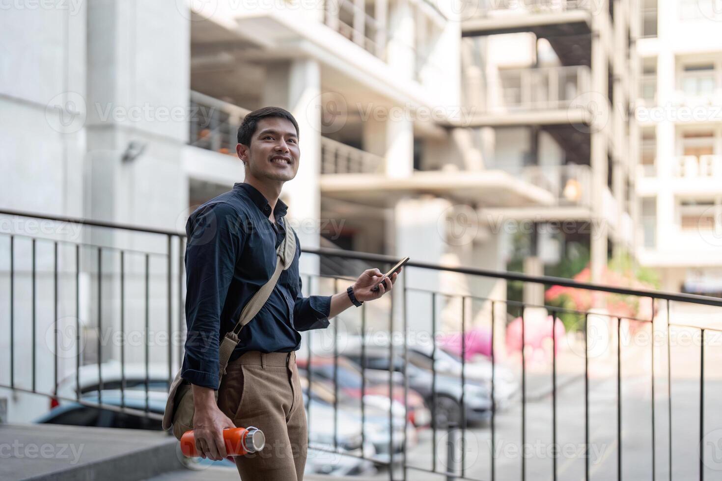 Smiling asian businessman walking to work while to hold reusable eco friendly ecological cup in the city photo