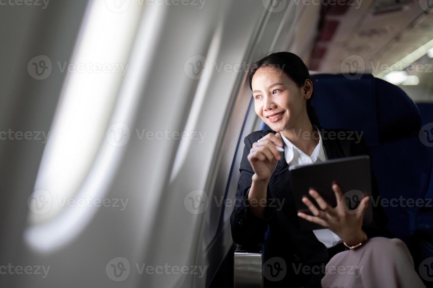 Successful young asian business woman sits in airplane cabin plane and working from anywhere. Flying at first class photo