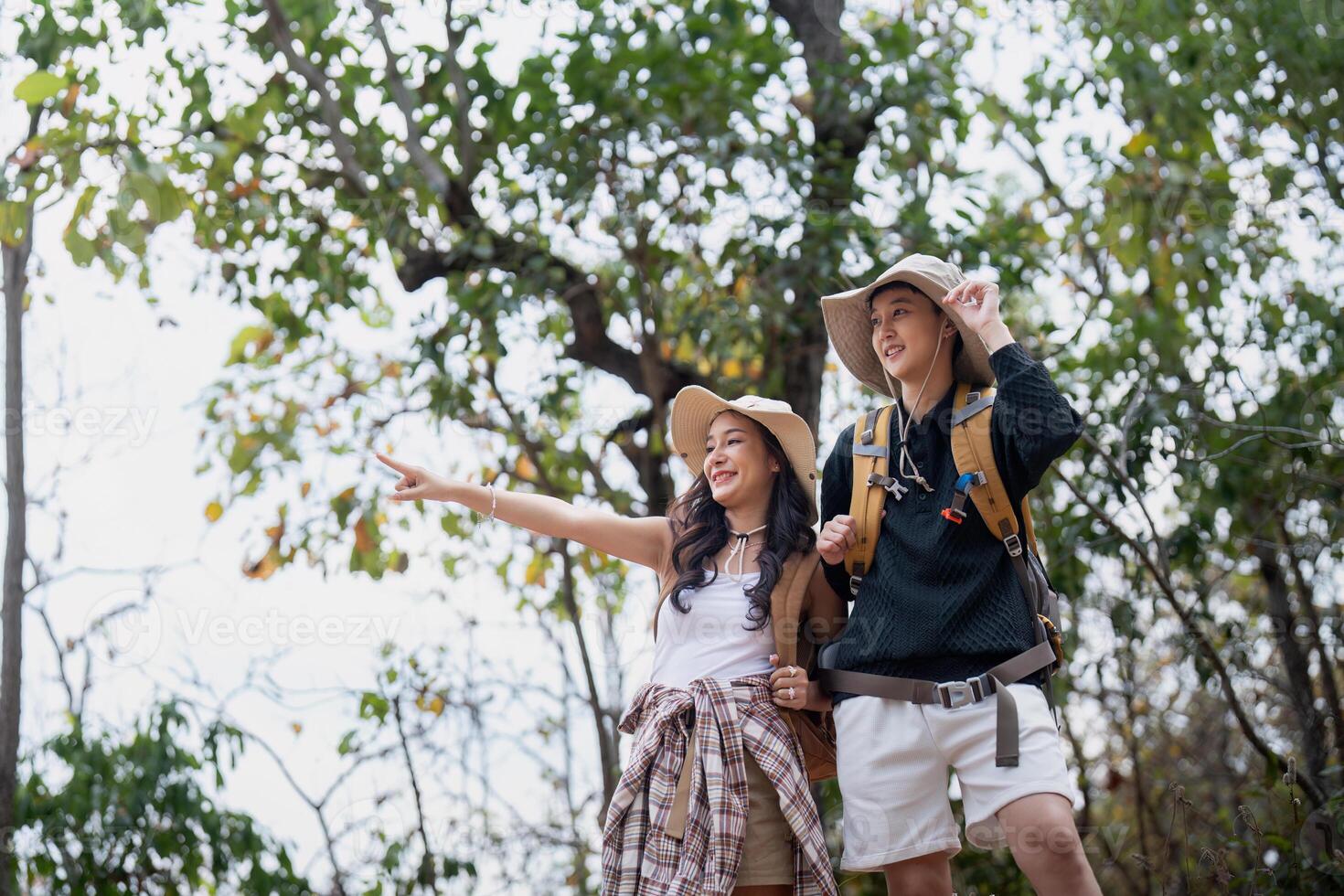 Cheerful romantic lesbian couple traveler with backpack on their backs go hiking through the forest in the mountains in summer photo