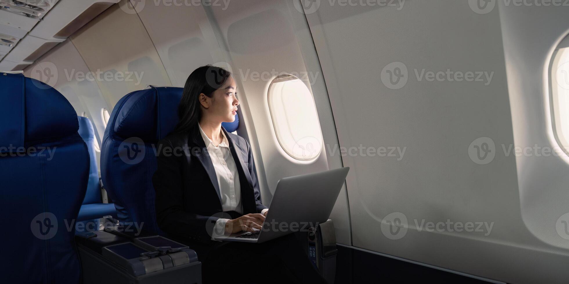 Successful young asian business woman sits in airplane cabin plane and working from anywhere. Flying at first class photo