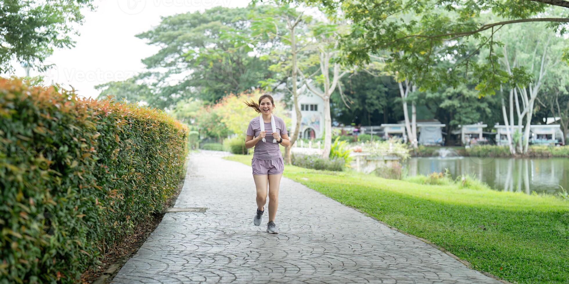 Woman active Asian woman in sportswear listening to music while running or jogging in the park in the morning photo