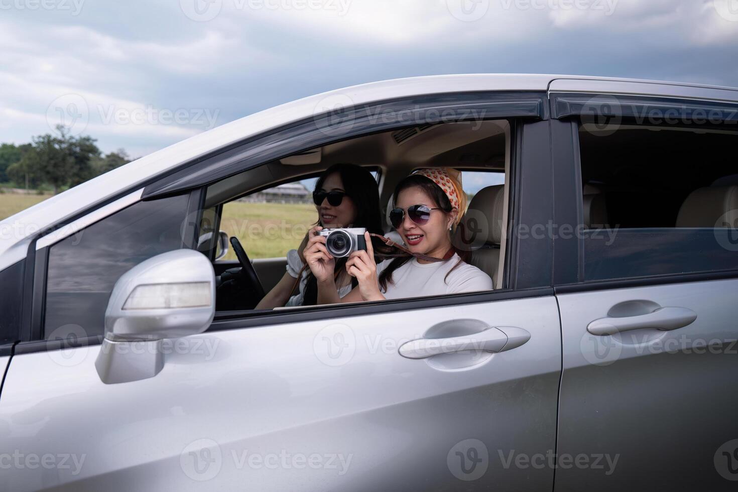 Young happy Asian girl friends laughing and smiling in car during a road trip to vacation photo