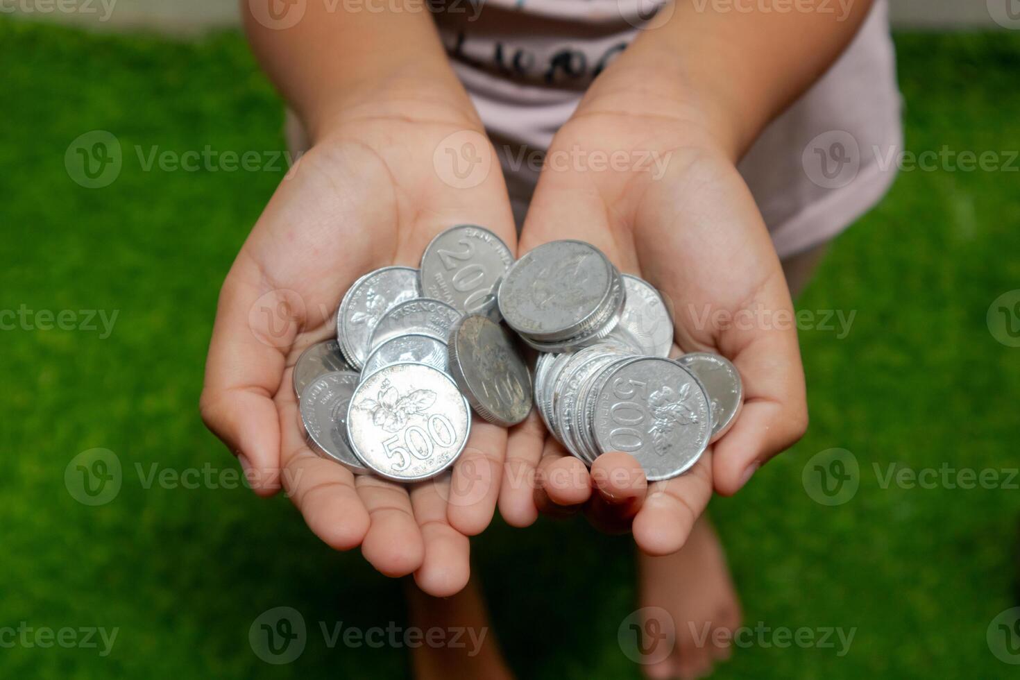 Indonesian coins in hands. Asian child holding Indonesian coin money. Saving money and investment concept. photo