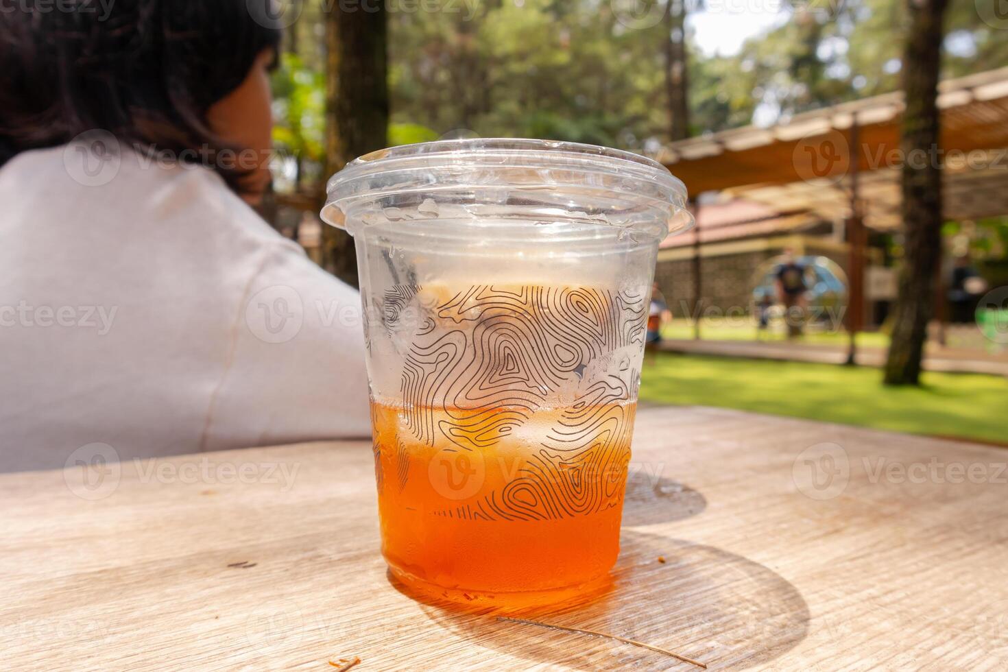 A fresh ice tea in takeaway cup in the table with nature background photo