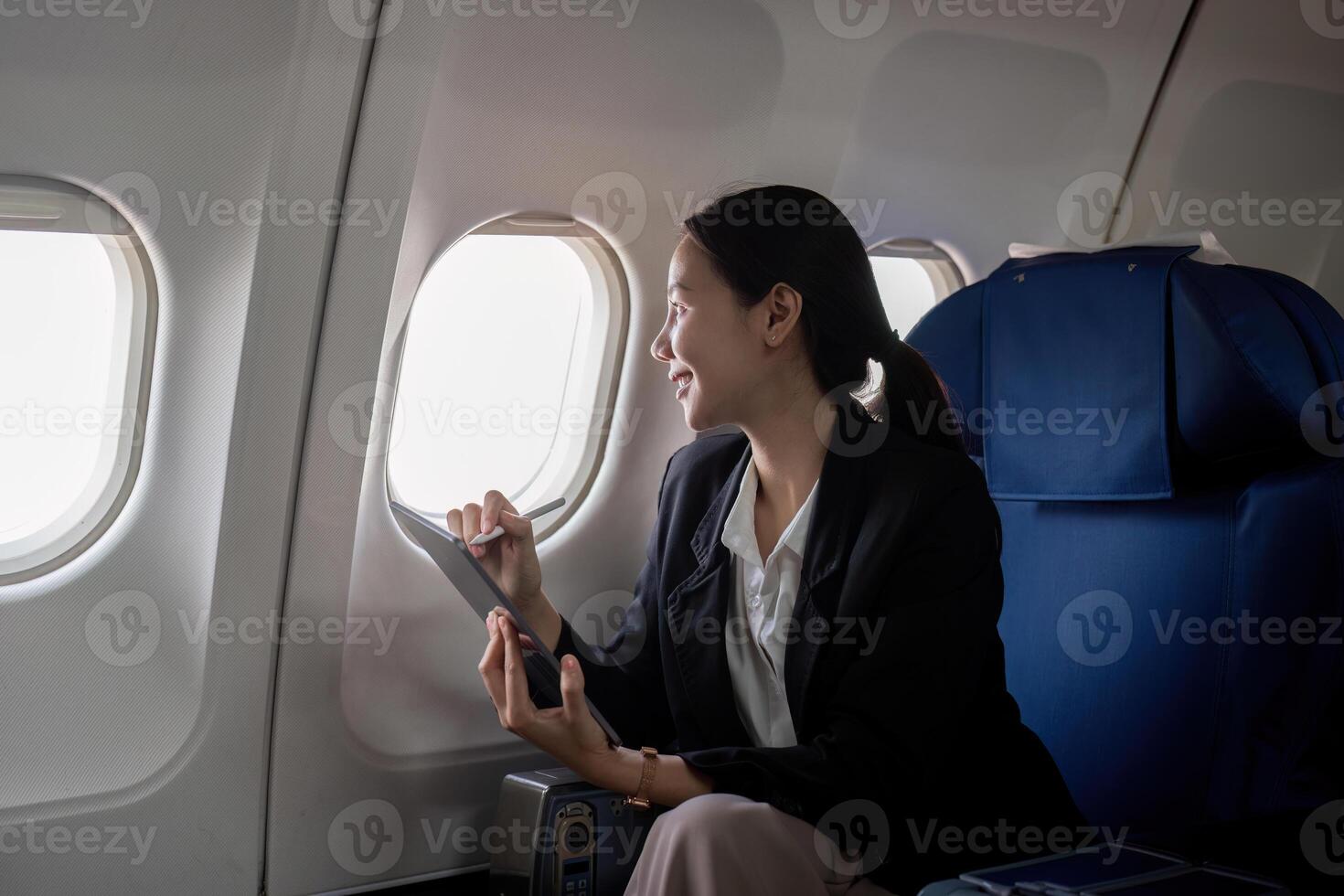 Successful young asian business woman sits in airplane cabin plane and working from anywhere. Flying at first class photo