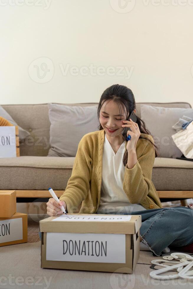 Woman asian preparing a delivery box with her used clothes, Donation and recycling concept photo