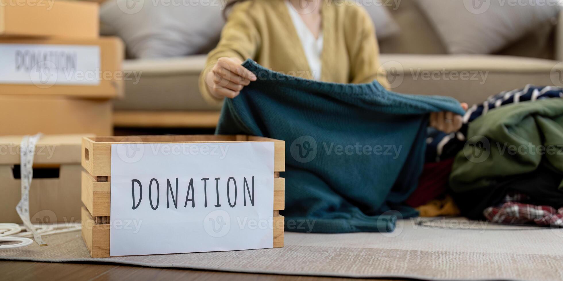 Donation, asian young woman sitting pack object at home, putting on stuff into donate box with second hand clothes, charity helping and needy people. Reuse recycle photo