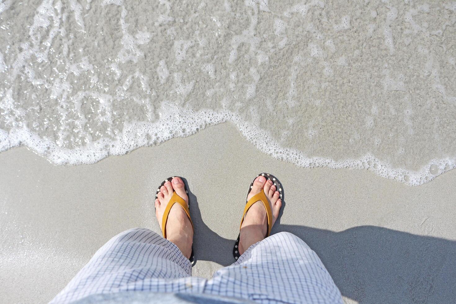 Man stands on the beach and the ocean waves are approaching him. photo