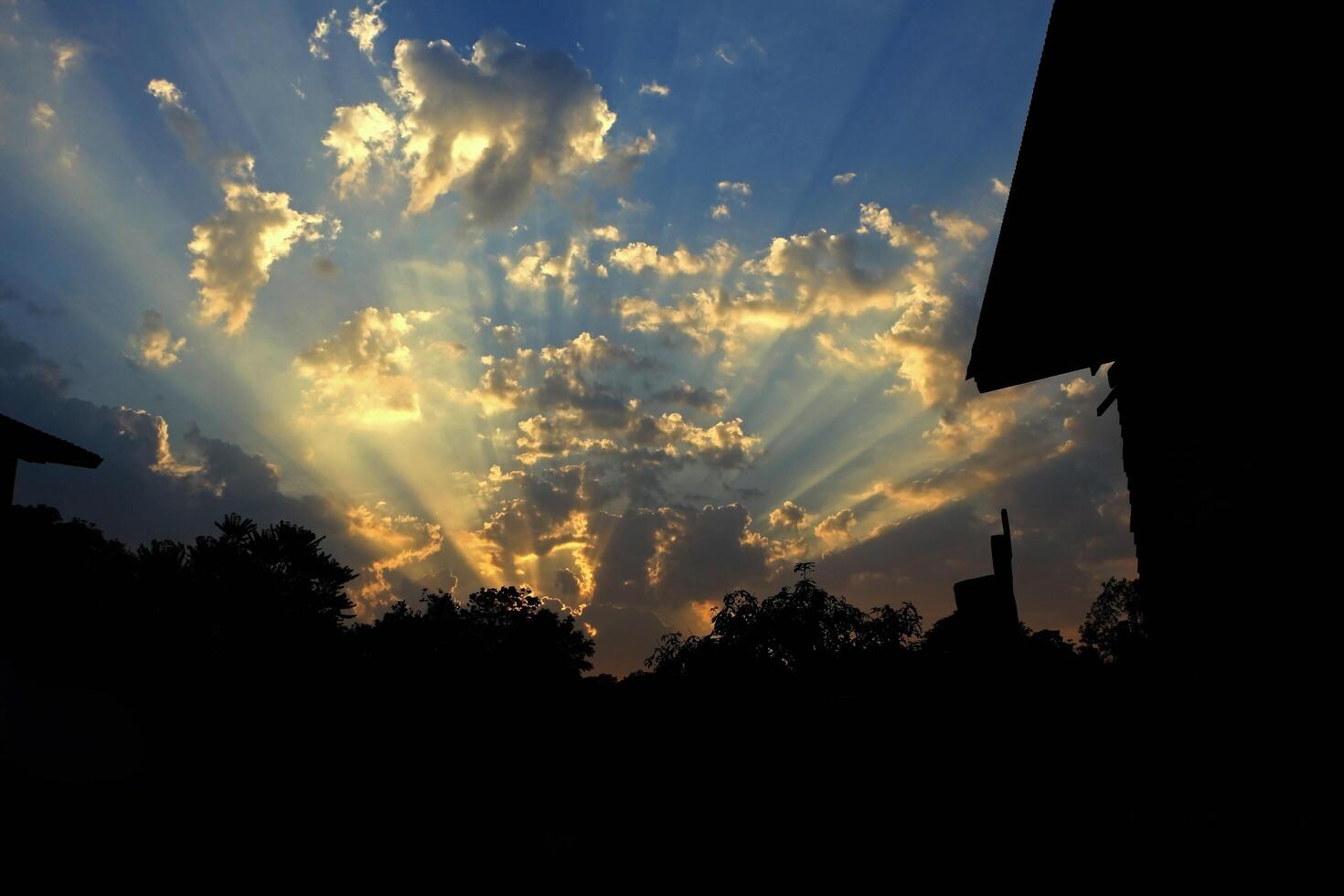 Silhouette of house and tree. Sunset or sunrise with sun rays light and cloud. Abstract of the blue sky in the evening. photo