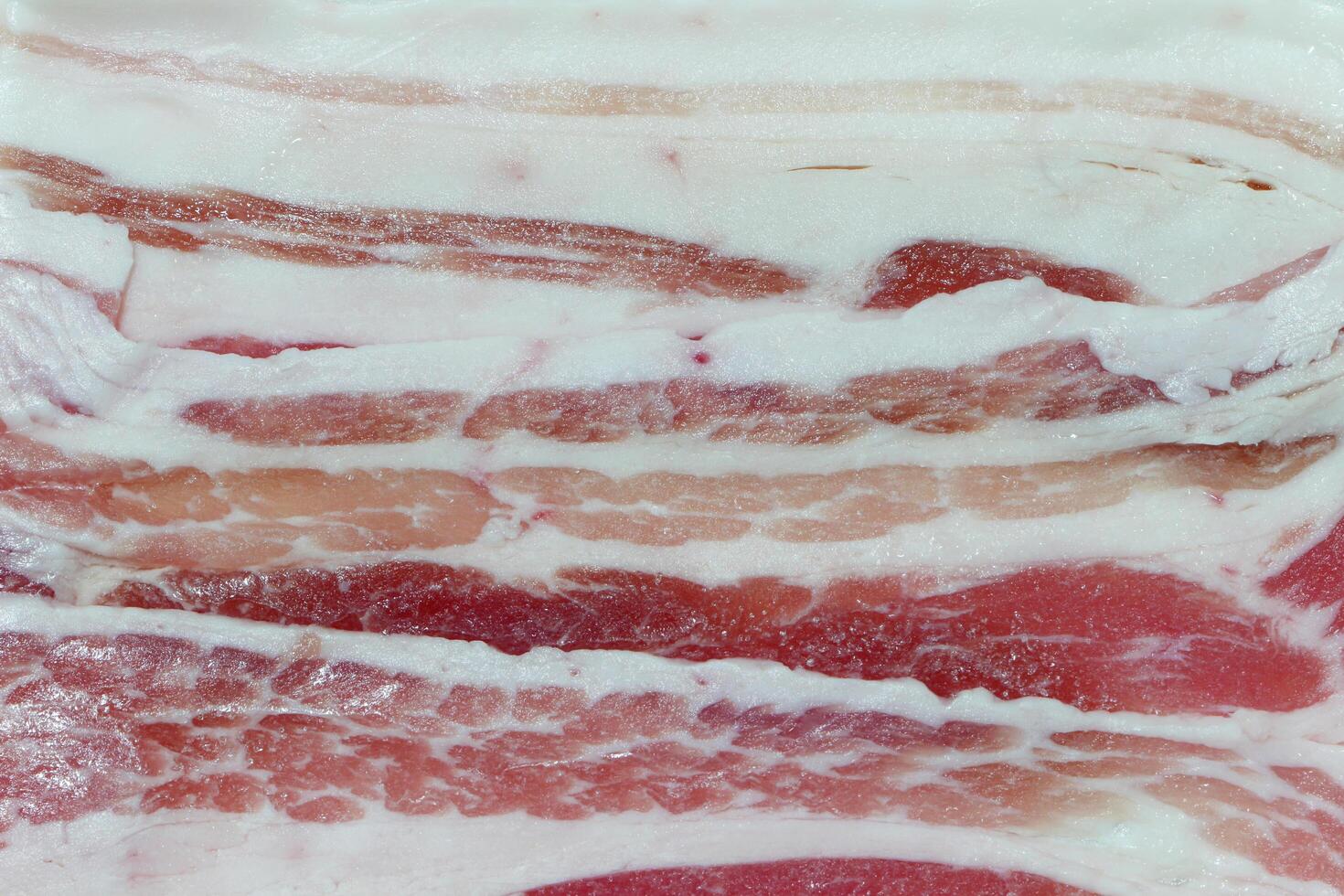 Meat from the sides and belly of a pig, having distinct strips of fat. Bacon, sliced pork texture background. photo