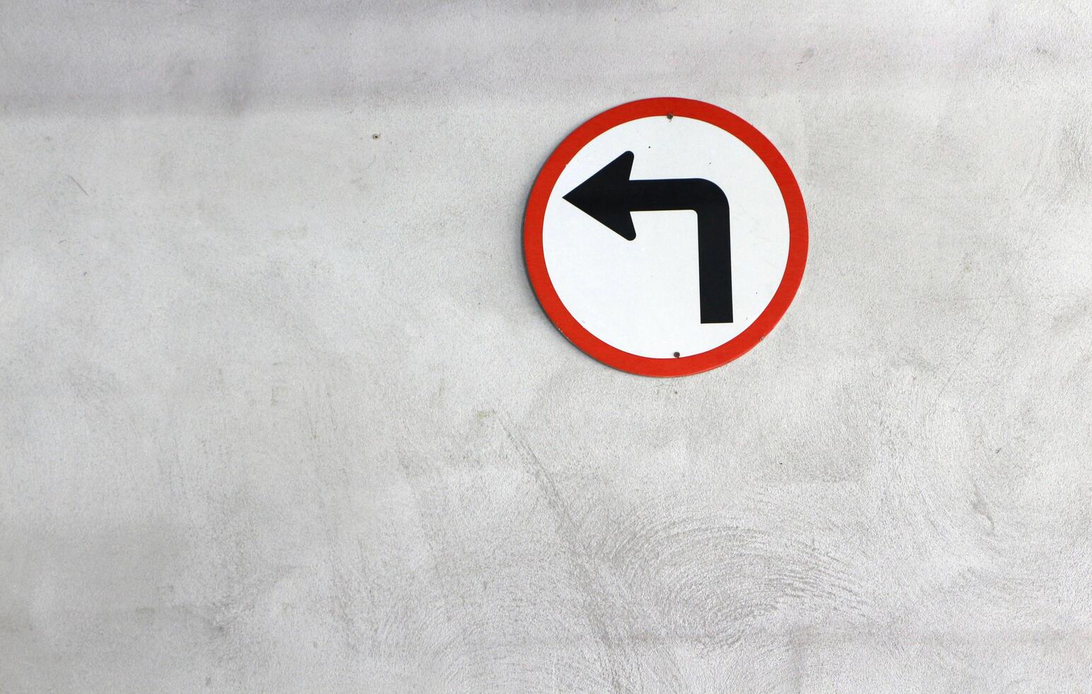 Traffic sign, turn left symbol on concrete wall background. photo