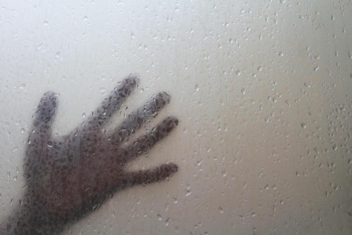 sombra de el del hombre mano detrás escarchado vaso con agua gotas. Víspera de Todos los Santos antecedentes. temor sentimiento. horror dedo. foto