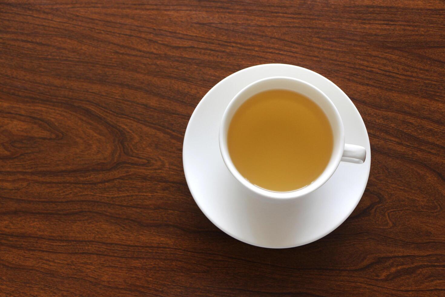 Ginger juice in white cup on wooden background. photo