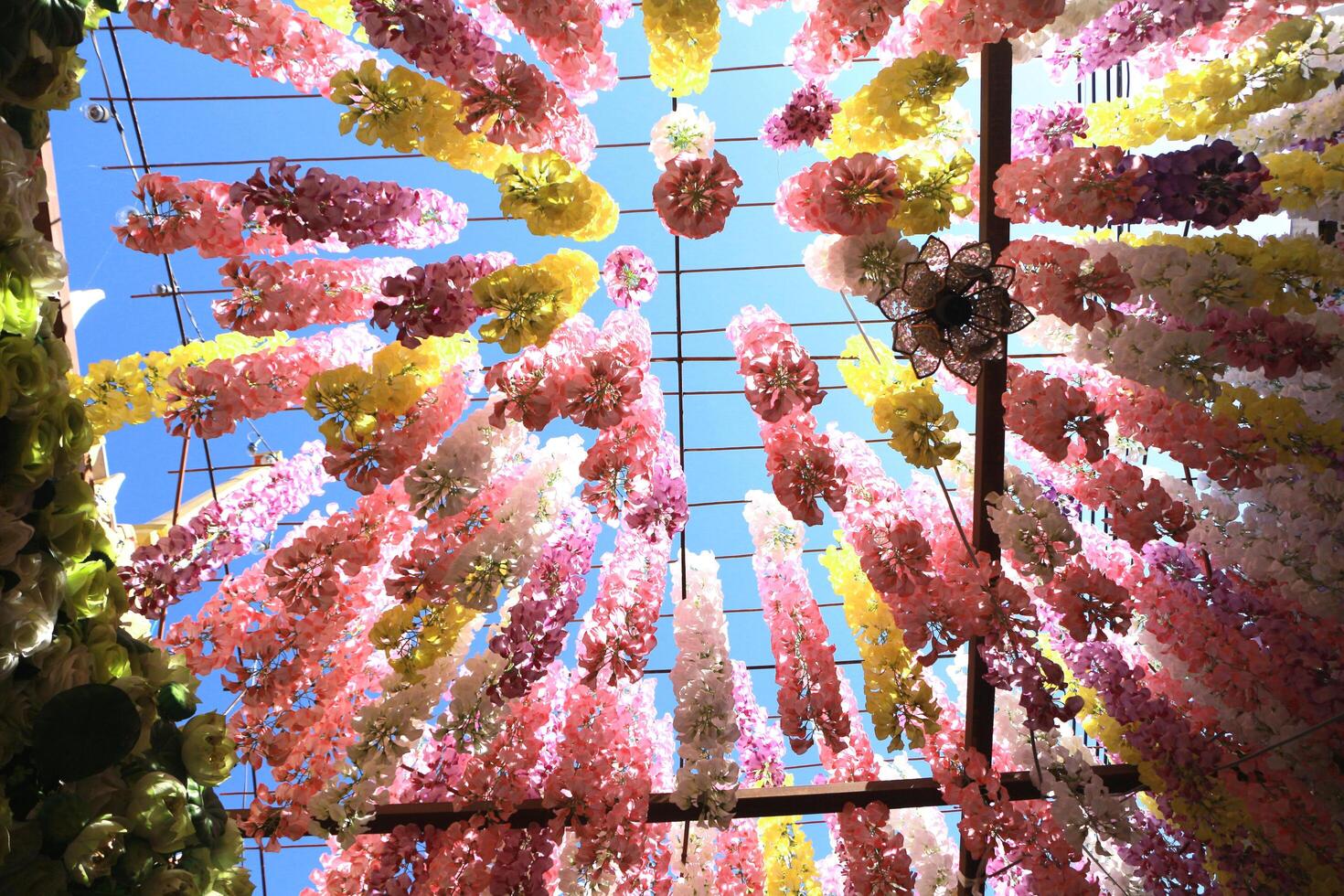 Looking up at a plastic flower hanging on a steel frame. It's beautiful, colorful. photo