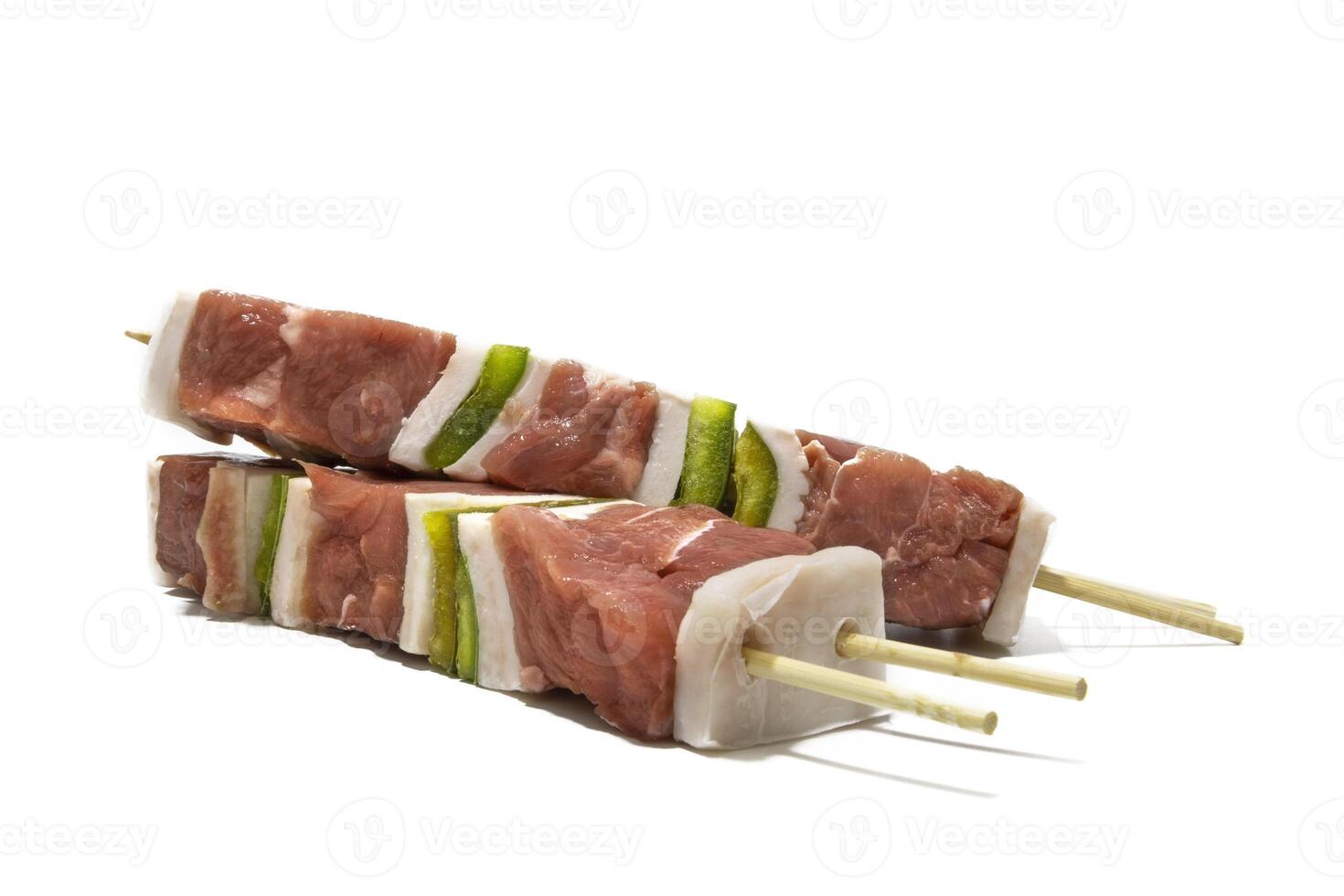 Raw meat and pepper skewers, isolated on a white background. Generally a skewer is made up of pieces of meat or fish interspersed with onion, pepper, mushrooms, etc. photo