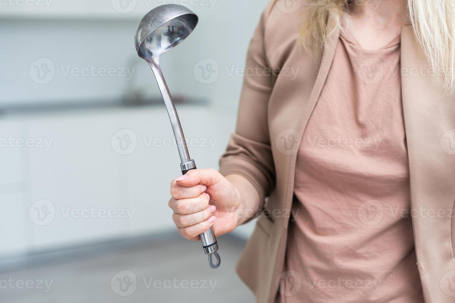 Metal kitchen ladle in hand, isolated on a white background photo