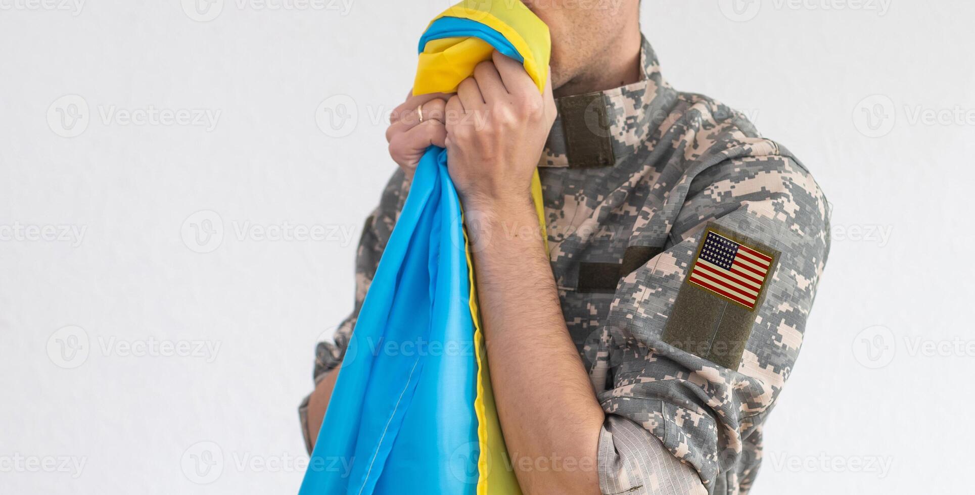 American Flag on Soldiers arm and flag of the Ukraine at background. US military support Ukraine photo