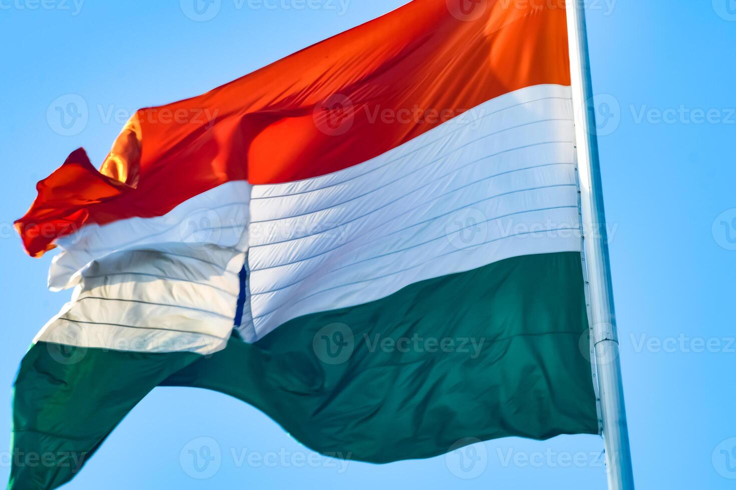 India flag flying high at Connaught Place with pride in blue sky, India flag fluttering, Indian Flag on Independence Day and Republic Day of India, tilt up shot, Waving Indian flag, Har Ghar Tiranga photo