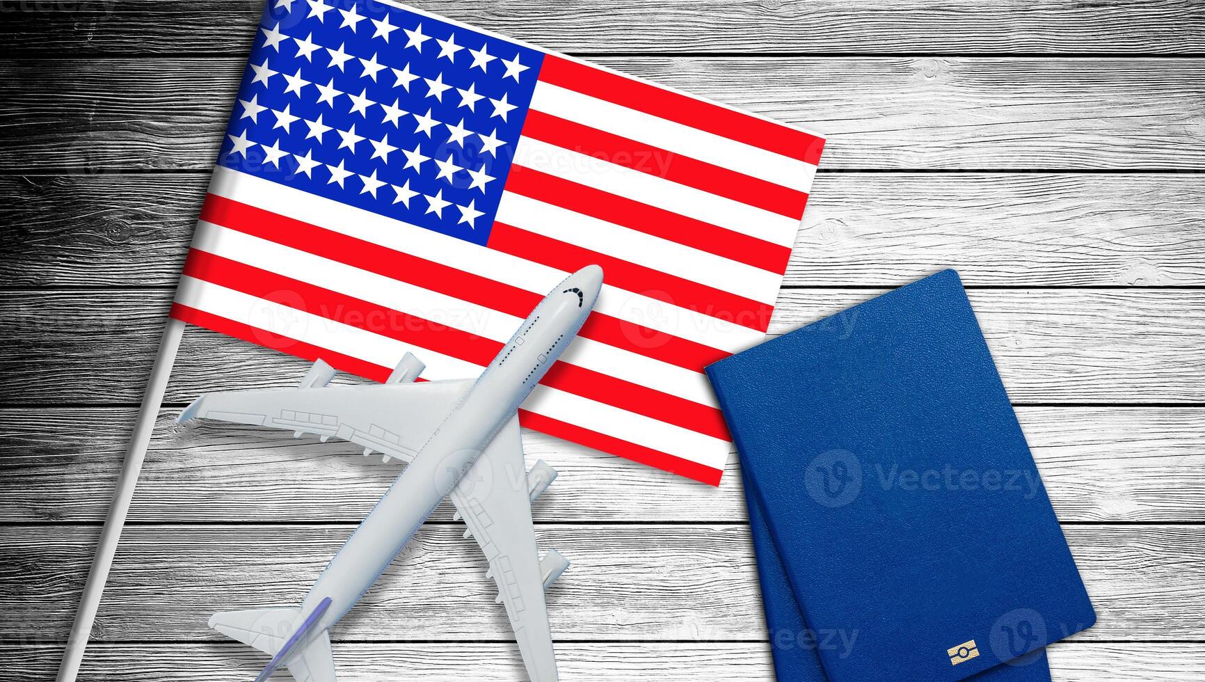 Plastic toy jet plane and flag of USA. American flag and grey toy air plane on wood close up. Flight to USA. photo