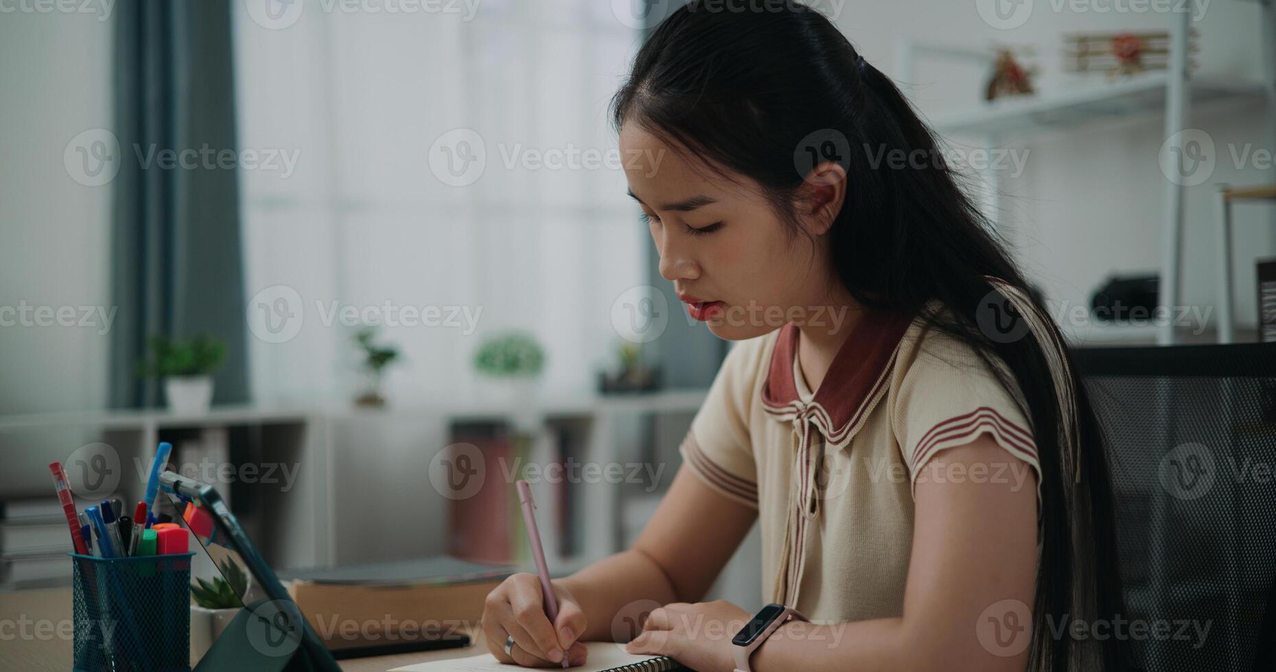 Selective focus, Side view, Female writer sitting at desk writing notes while working on tablet for online learning at home, creative thoughts to journaling, idea and inspiration photo